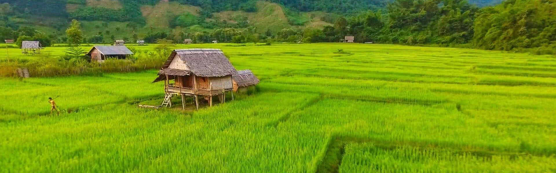 Tranquil Muang La riverside in Laos on a scenic Muang La Travel banner by Legend Travel Group.